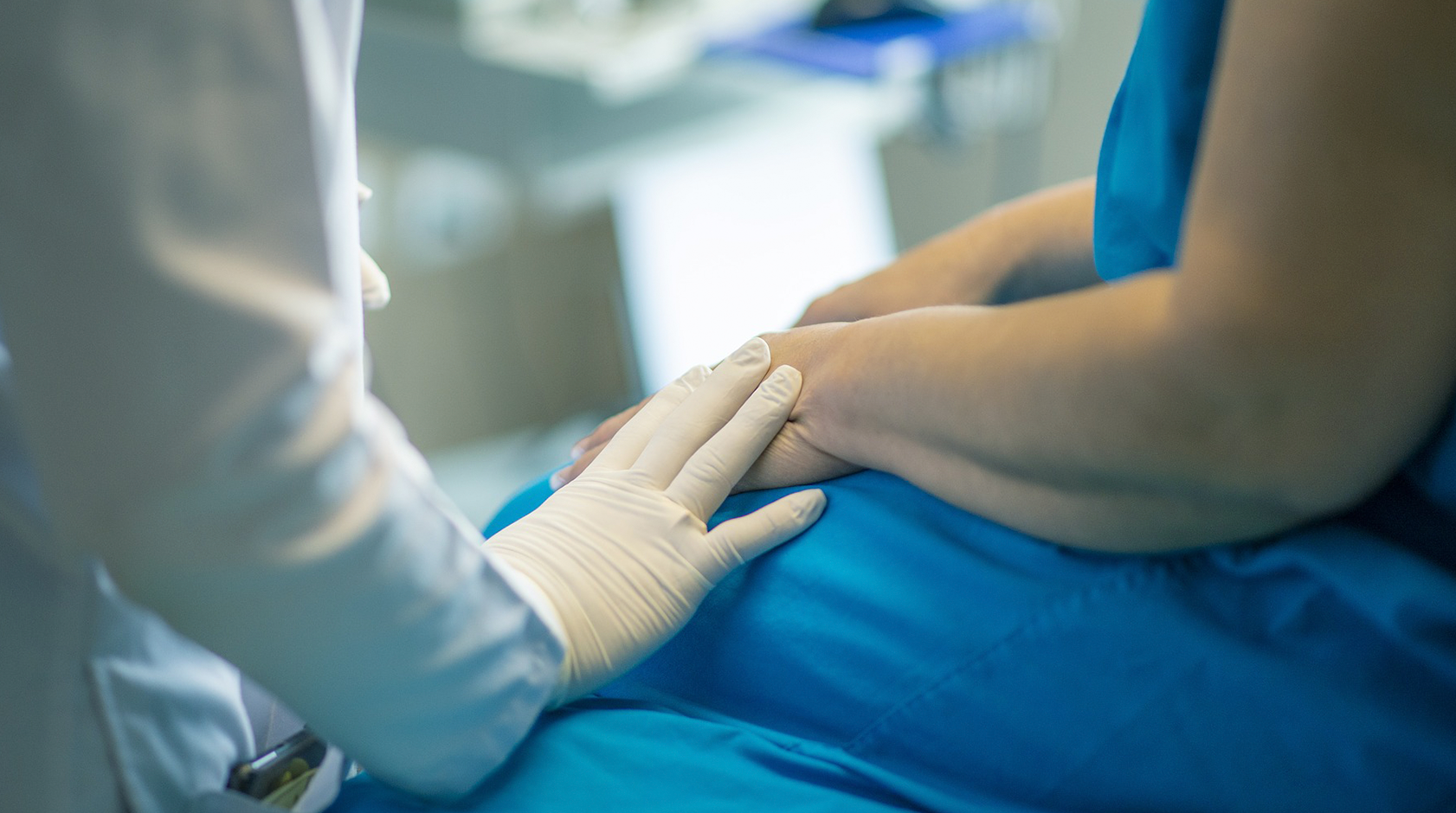 Doenças raras: médico colocando a mão em um paciente durante um atendimento no hospital. Seus rostos não aparecem na imagem