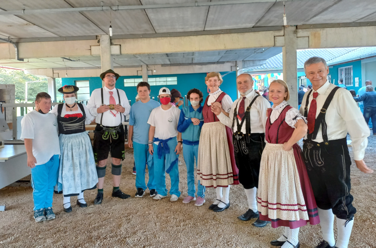 O grupo folclórico está posando para a foto. Entre eles estão alguns alunos da instituição